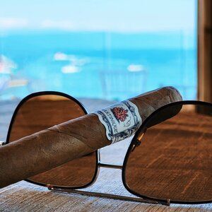 Martinique Lancero cigar with sunglasses overlooking ocean view from high-rise window