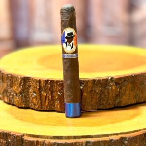Harlem Renaissance Habano Oscuro cigar with blue band displayed on wooden circular stand against blurred background.