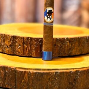 Harlem Renaissance Sumatra Toro cigar displayed on wooden rounds with blue band and silhouette logo.