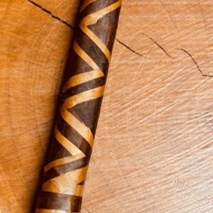 Handcrafted wooden pipe with dark brown and tan striped design, featuring curved stem and bowl, displayed on wooden surface.