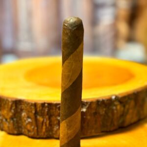 House Blend Corona Double Wrap cigar displayed on yellow surface with wooden cross-section backdrop