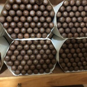 Six boxes of premium torpedo cigars with cubanofiller criollo ligero, displaying tightly rolled brown cigars arranged in white paper-lined packaging on woode…