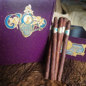 Three Flechette cigars displayed with purple branded packaging and furry texture surface against dark background.