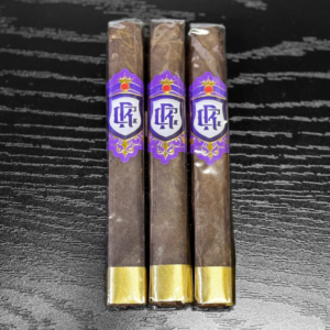Three premium Royalty Toro cigars with purple and gold bands featuring ornate crown logo displayed on textured black surface.