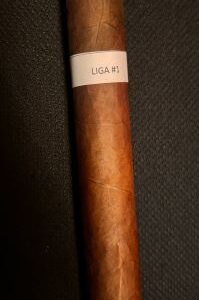 Nicaraguan Liga No 1 cigar with brown wrapper and white band label on textured dark background.
