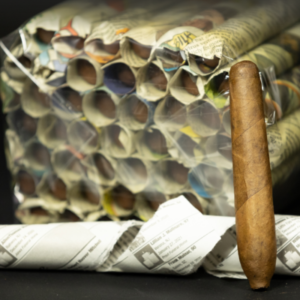 Newspaper PT Strung Sumatra Super Premium cigar displayed with its distinctive wrapper and wooden foot on dark background.